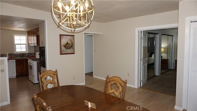 dining room with sink, a notable chandelier, and light wood-type flooring