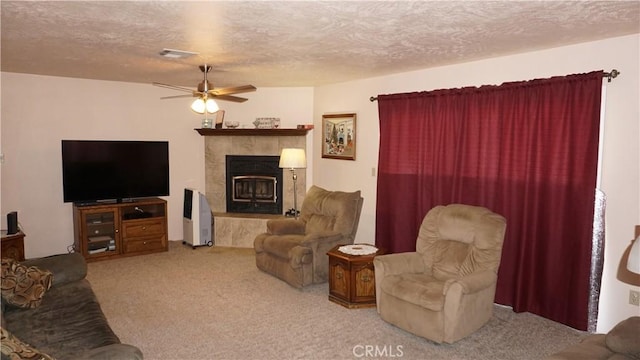 carpeted living room featuring ceiling fan, a textured ceiling, and a tiled fireplace