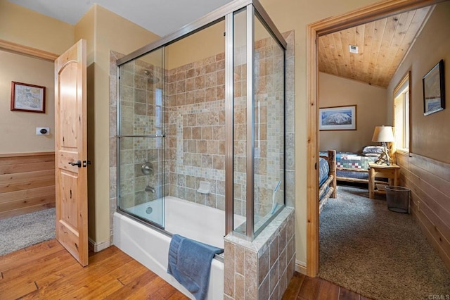 bathroom with hardwood / wood-style flooring, wooden walls, bath / shower combo with glass door, vaulted ceiling, and wood ceiling