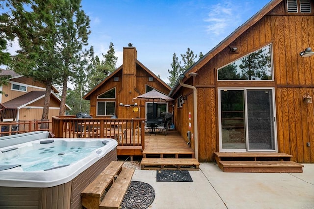 wooden deck featuring a hot tub and a patio