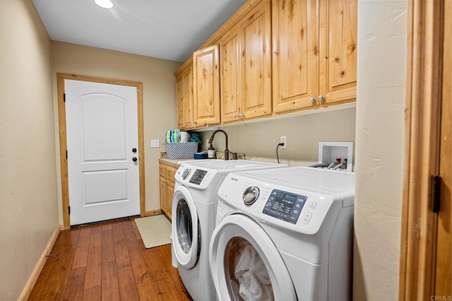 laundry area featuring hardwood / wood-style flooring, washer and clothes dryer, sink, and cabinets