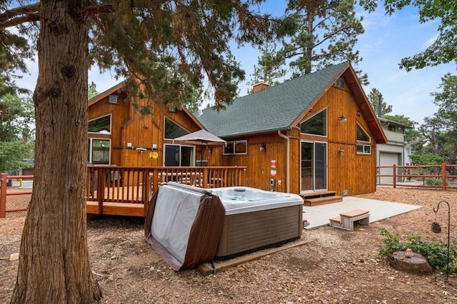 rear view of property featuring a hot tub and a deck