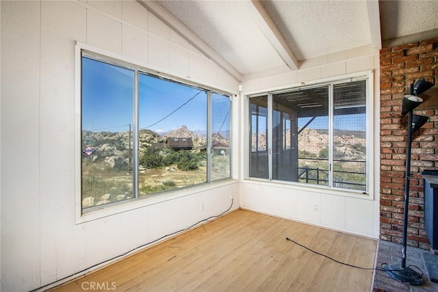 unfurnished sunroom featuring vaulted ceiling with beams