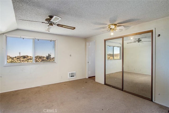 unfurnished bedroom featuring light colored carpet, vaulted ceiling, a closet, and ceiling fan