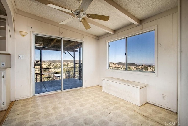 interior space with beam ceiling, ceiling fan, and a textured ceiling