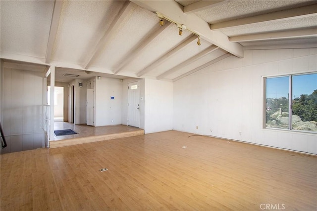 unfurnished living room featuring wood-type flooring and lofted ceiling with beams