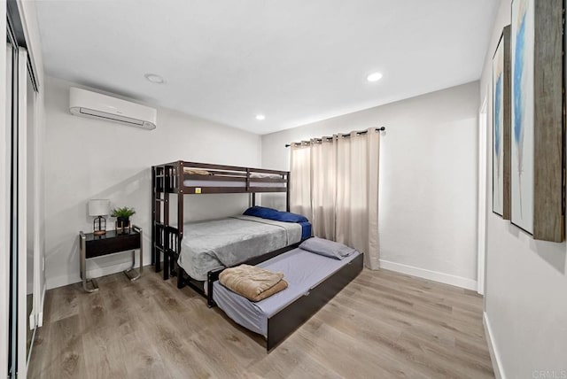 bedroom with a wall unit AC and light hardwood / wood-style floors