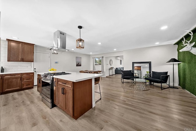 kitchen with decorative light fixtures, gas stove, light hardwood / wood-style floors, and range hood