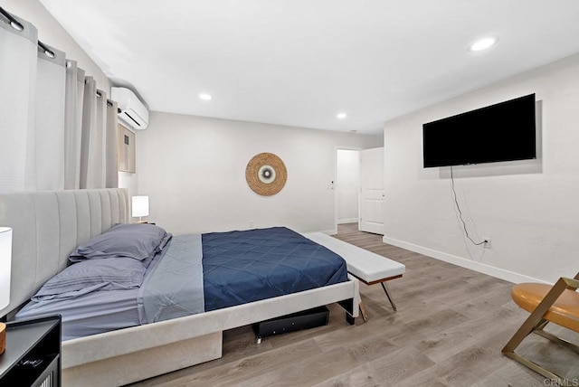 bedroom with light hardwood / wood-style floors and a wall mounted AC