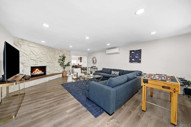 living room with a wall mounted air conditioner, light hardwood / wood-style flooring, and a fireplace