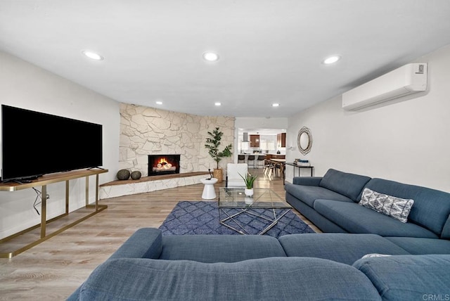 living room with light wood-type flooring, a fireplace, and a wall mounted AC