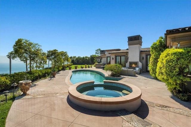 view of swimming pool featuring an in ground hot tub, a patio, and an outdoor fireplace