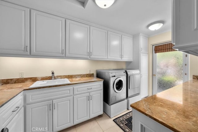 clothes washing area with washing machine and clothes dryer, light tile patterned floors, cabinets, and sink