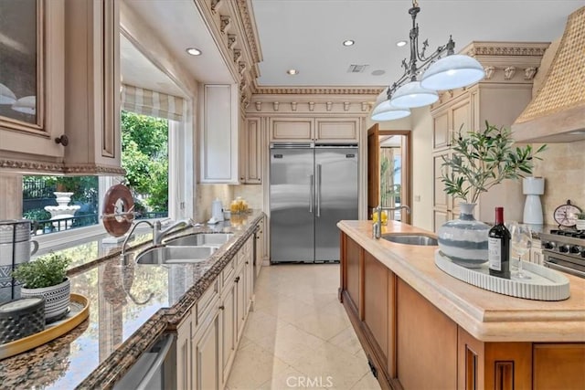 kitchen with stainless steel built in fridge, custom range hood, sink, and a wealth of natural light