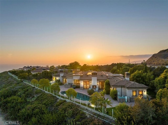 back house at dusk featuring a fenced in pool and a patio area