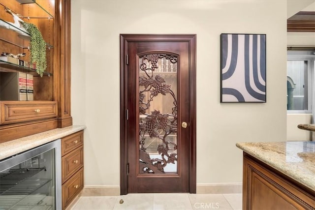 interior space with light stone countertops, light tile patterned floors, and beverage cooler