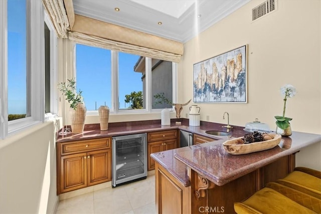 bar featuring a wealth of natural light, light tile patterned floors, ornamental molding, and beverage cooler