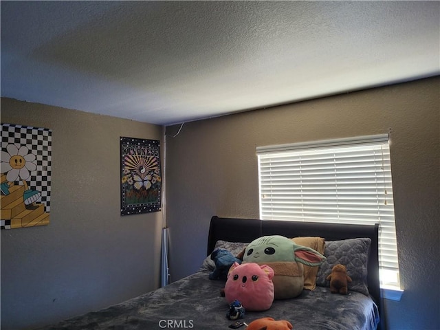 bedroom with a textured ceiling and multiple windows