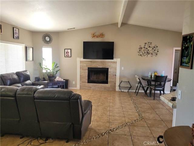 living room featuring light tile patterned floors, lofted ceiling with beams, and a tiled fireplace