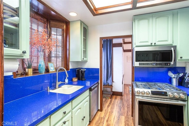 kitchen featuring light wood-type flooring, dark stone counters, sink, and stainless steel appliances