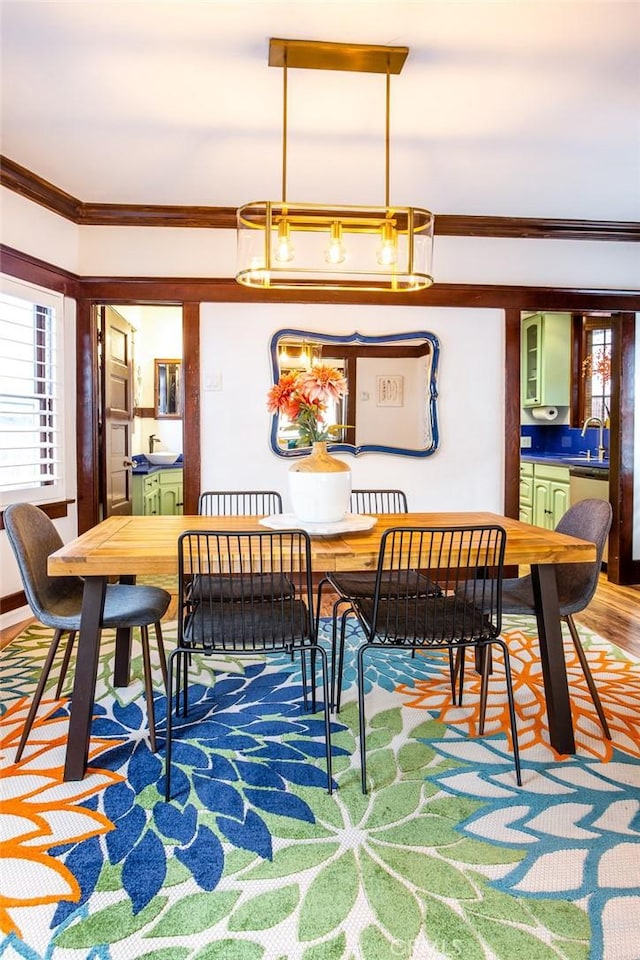 dining space featuring wood-type flooring, sink, and ornamental molding