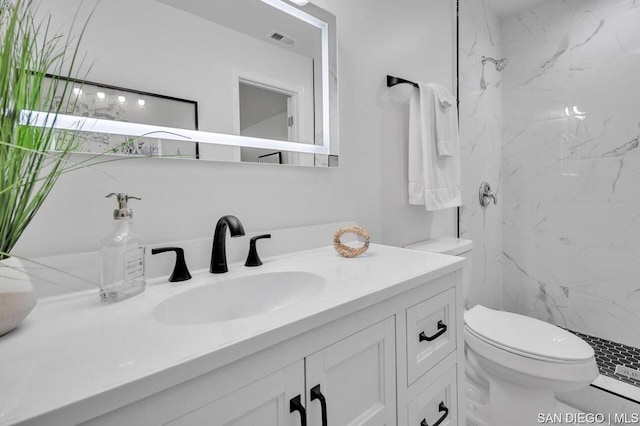 bathroom with tiled shower, toilet, and vanity