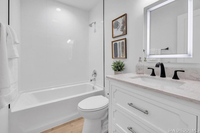 full bathroom with toilet, hardwood / wood-style floors, tiled shower / bath combo, and vanity