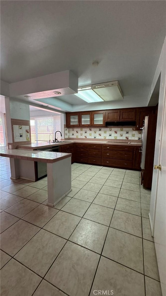 kitchen with decorative backsplash, sink, a breakfast bar area, and light tile patterned flooring