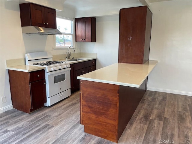 kitchen with kitchen peninsula, gas range gas stove, sink, and light hardwood / wood-style flooring