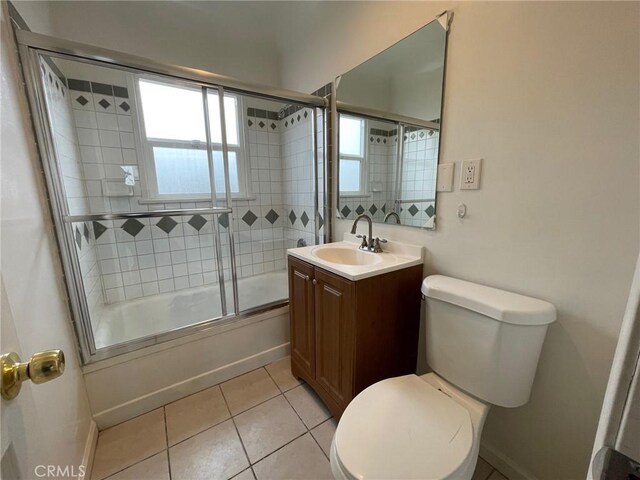 full bathroom with tile patterned floors, toilet, vanity, and combined bath / shower with glass door