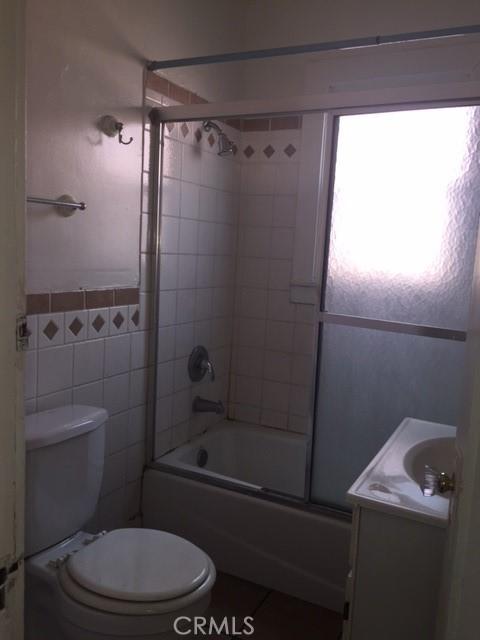 full bathroom with shower / bath combination with glass door, tile patterned floors, vanity, and toilet