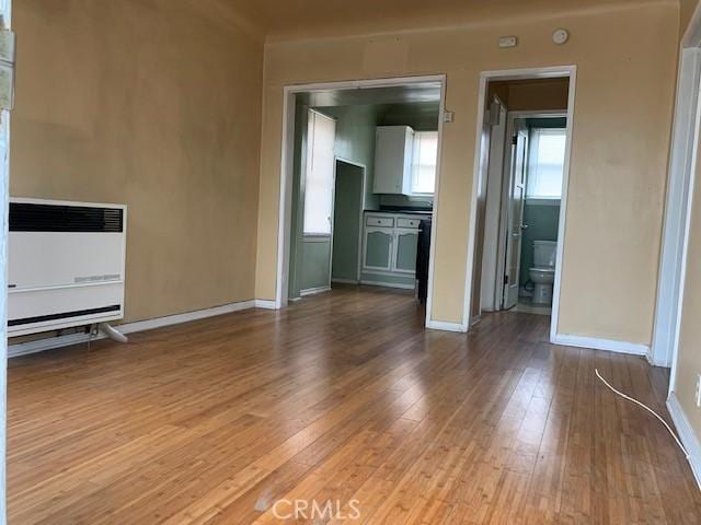 unfurnished living room featuring heating unit and light wood-type flooring