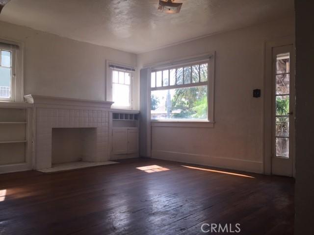 unfurnished living room featuring dark hardwood / wood-style flooring and a brick fireplace