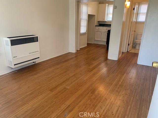 unfurnished living room with heating unit and wood-type flooring