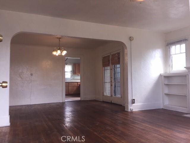 empty room with a chandelier and dark wood-type flooring