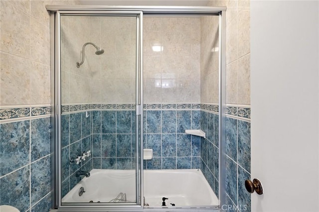 bathroom featuring bath / shower combo with glass door and tile walls