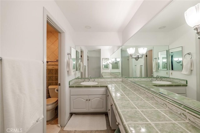 bathroom with toilet, tile walls, vanity, and a notable chandelier