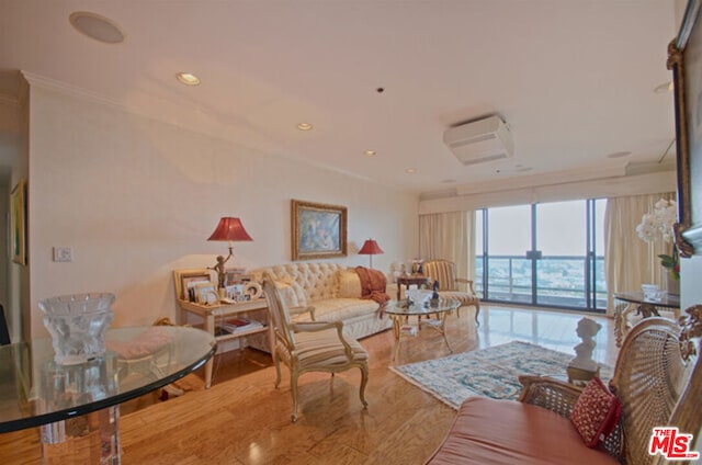 living room with crown molding, expansive windows, a wall mounted air conditioner, and light wood-type flooring