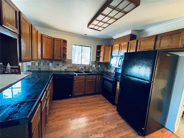 kitchen with black appliances, sink, crown molding, hardwood / wood-style flooring, and decorative backsplash