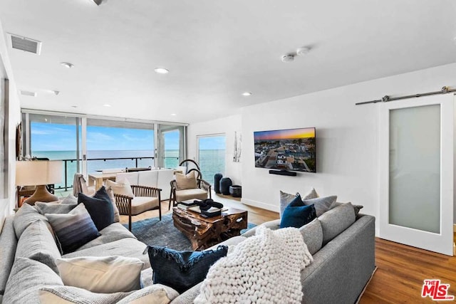 living room featuring a barn door, a water view, and dark wood-type flooring