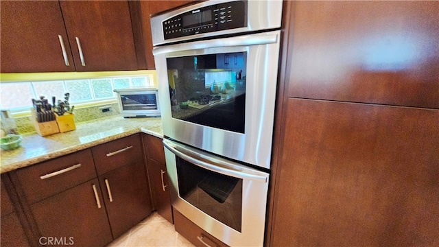 kitchen with backsplash, double oven, white fridge, and light stone counters