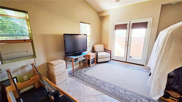 living room with french doors, light tile flooring, and lofted ceiling