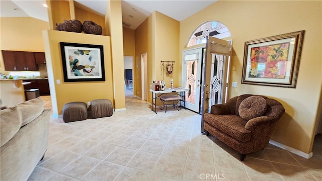 living area featuring high vaulted ceiling, light tile floors, and french doors