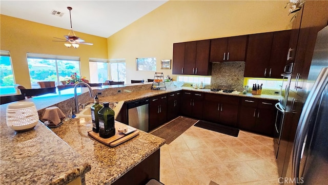 kitchen with backsplash, ceiling fan, high vaulted ceiling, stainless steel appliances, and light stone counters