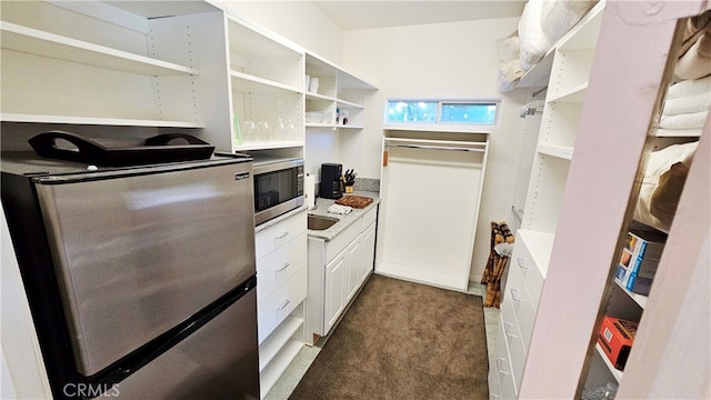 interior space featuring stainless steel fridge, white cabinets, and dark carpet