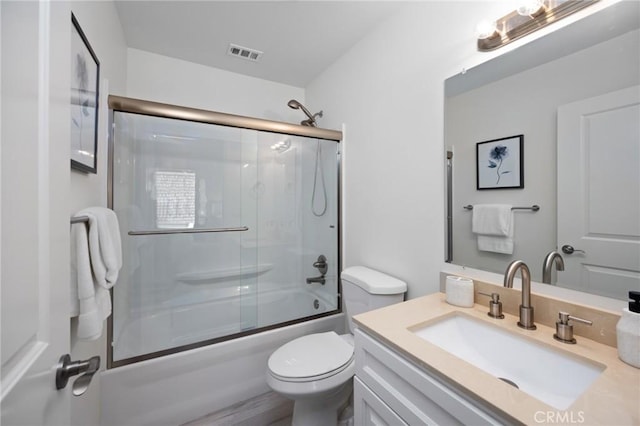 full bathroom with vanity, toilet, and bath / shower combo with glass door