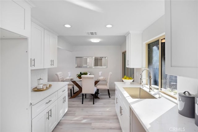 kitchen featuring white cabinets, light hardwood / wood-style floors, and sink