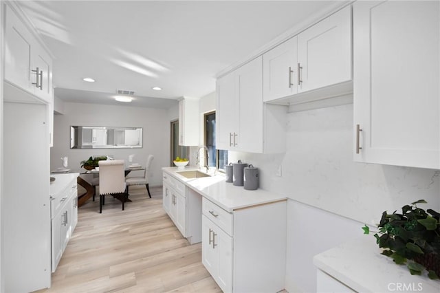 kitchen with white cabinets, decorative backsplash, sink, and light hardwood / wood-style flooring