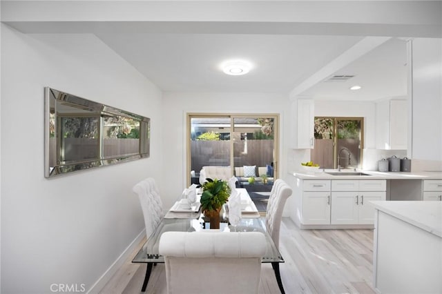 dining space featuring light wood-type flooring, a healthy amount of sunlight, and sink