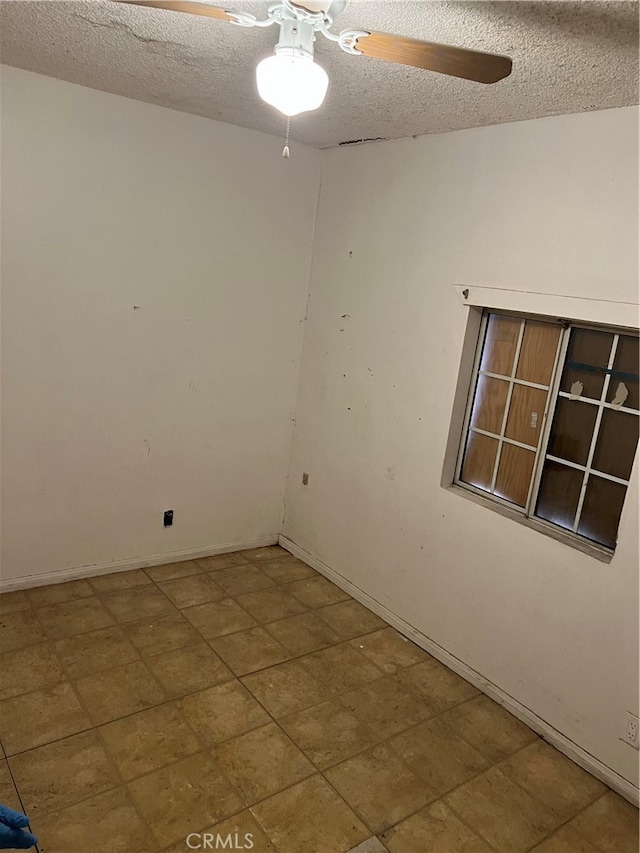 unfurnished room with ceiling fan and a textured ceiling